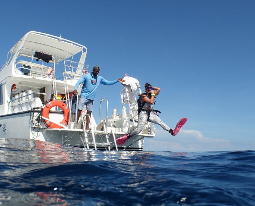 Woman jumping off boat with diving gear